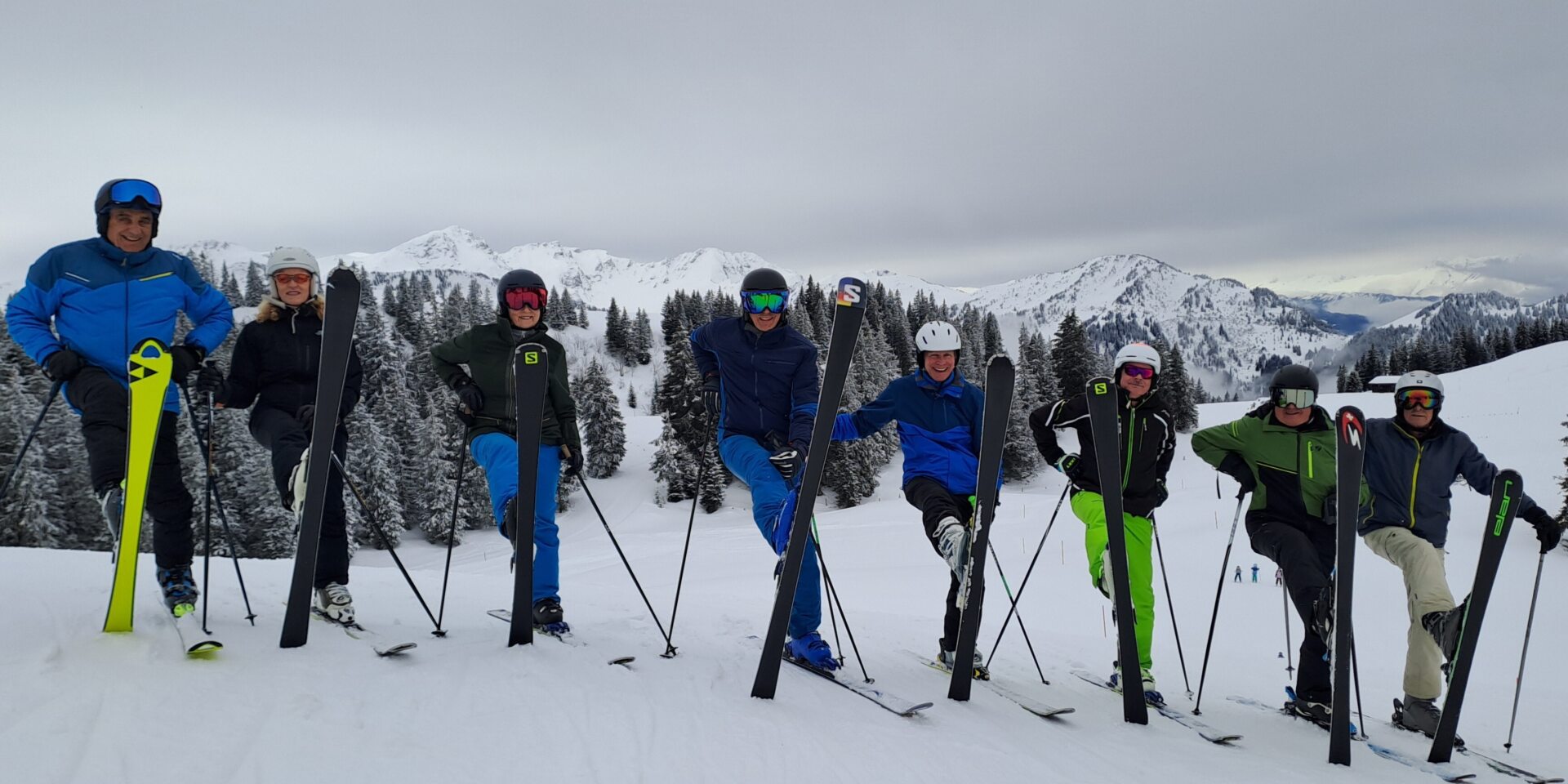 Skistamm: Acht Skifahrer stehen nebeneinander mit aufgestelltem Ski