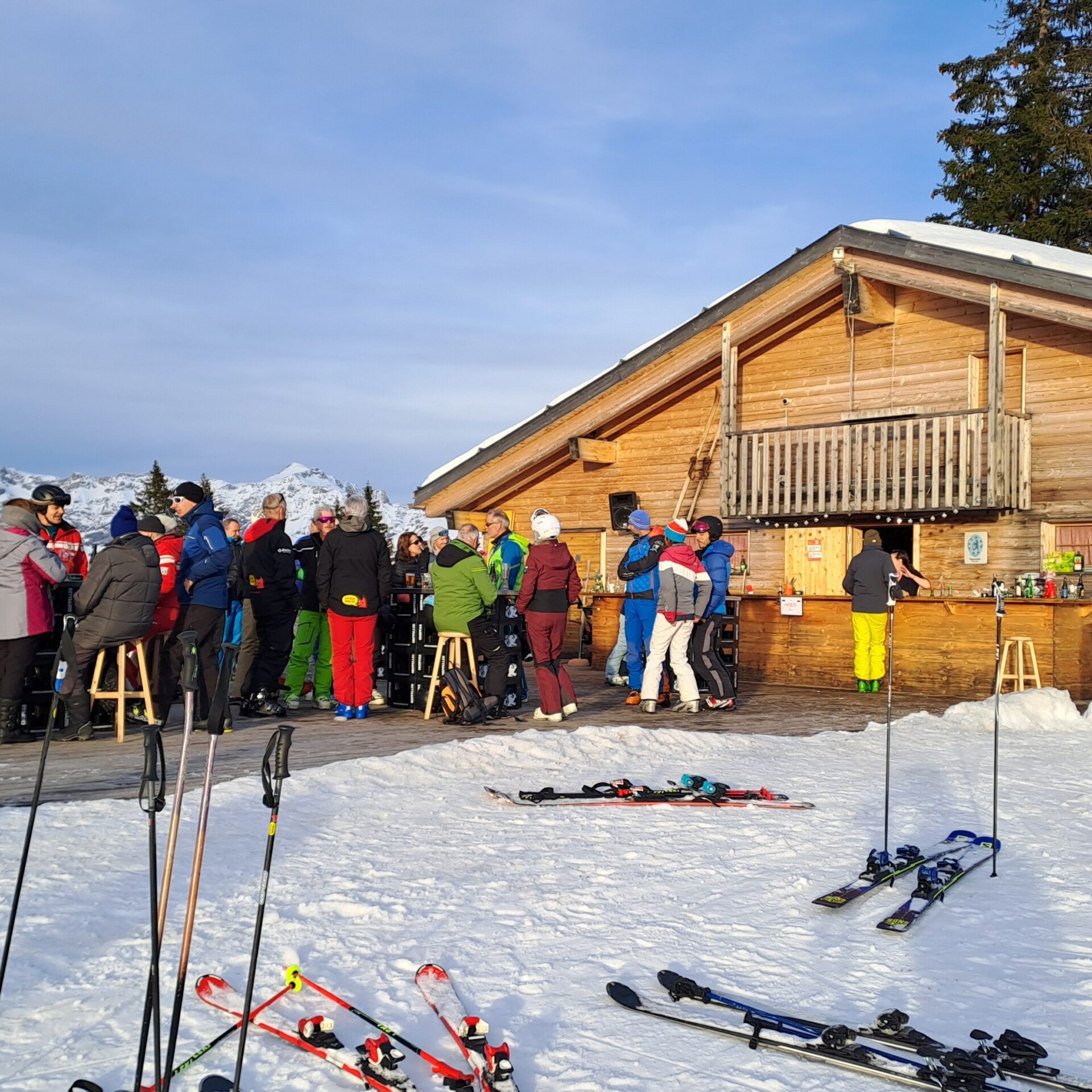 Red Fox Terasse mit Leuten und Ski mit Stöcken im Vordergrund