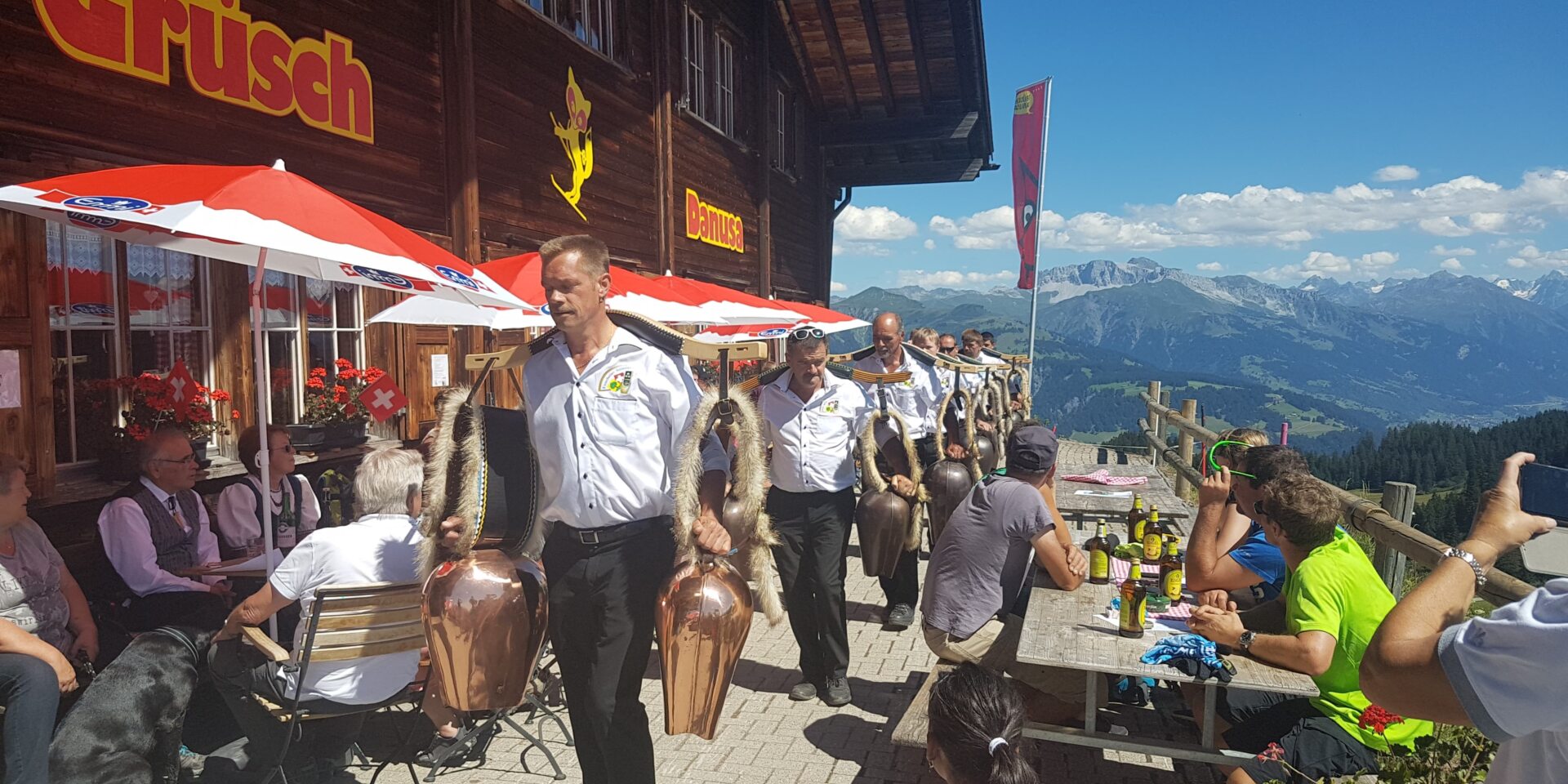 Einscheller auf der Terrasse des Berghauses mit Panorama im Hintergrund