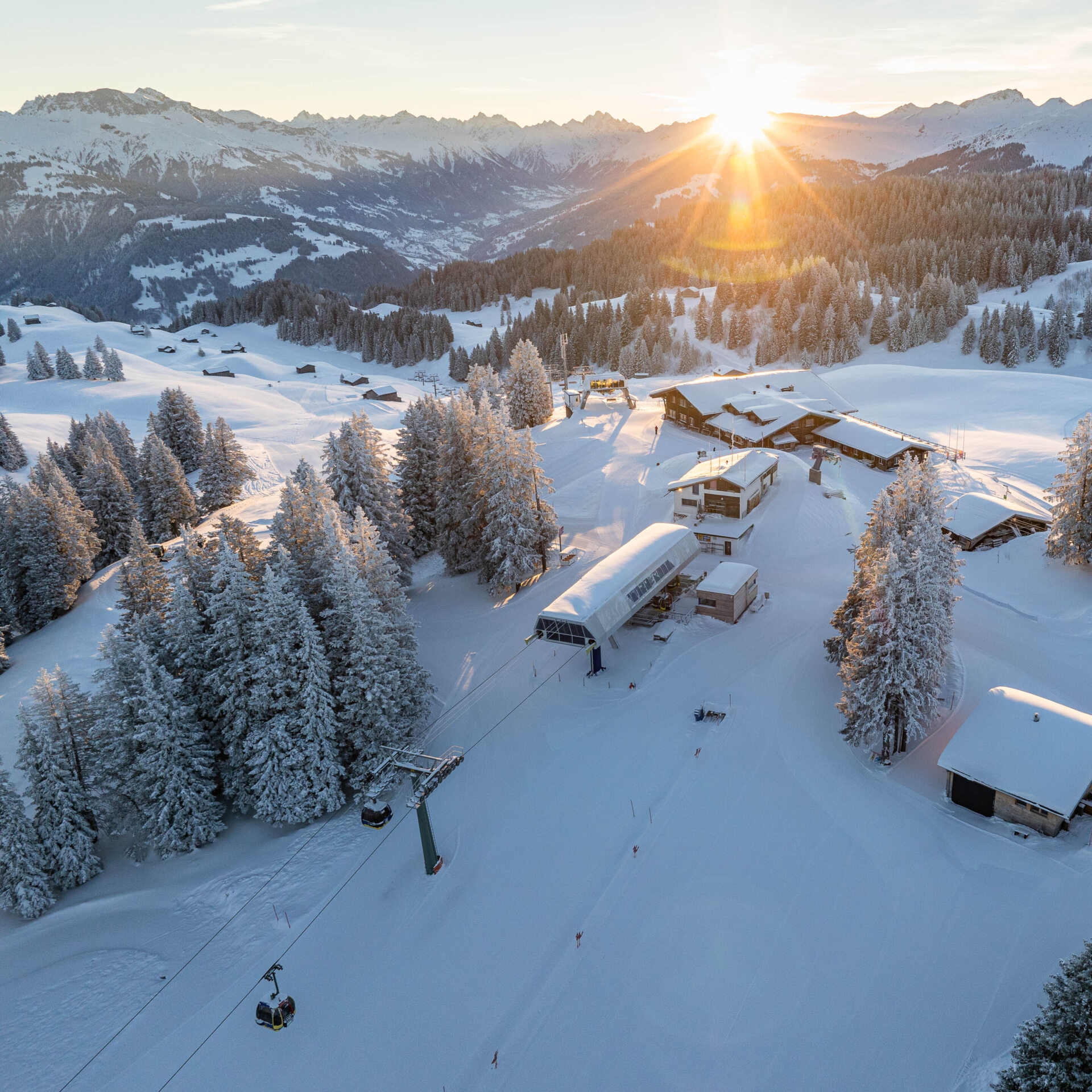 Drohnenfoto vom Berg mit Lift Berghaus und Sonnenaufgang