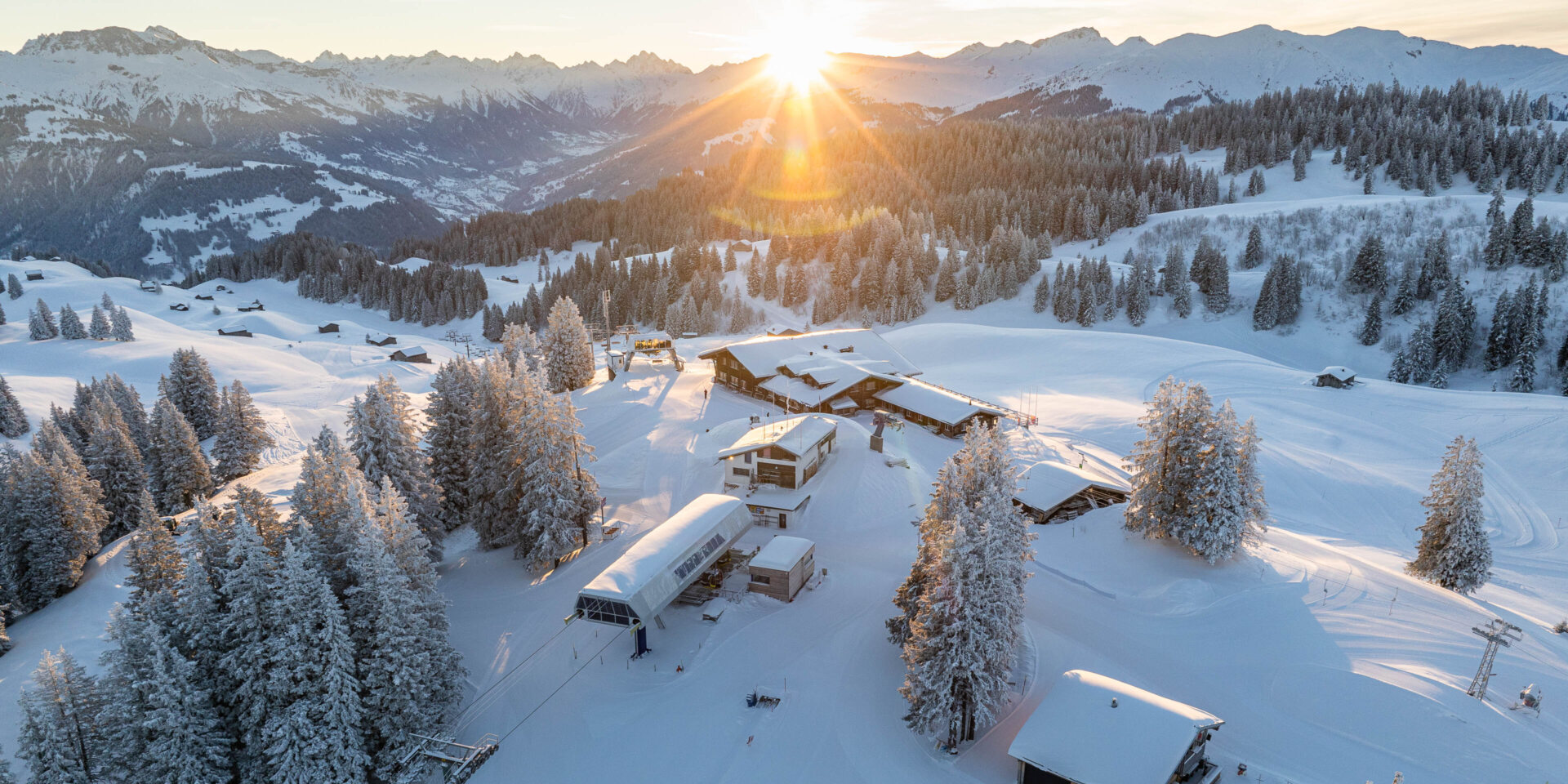 Drohnenfoto vom Berg mit Lift Berghaus und Sonnenaufgang