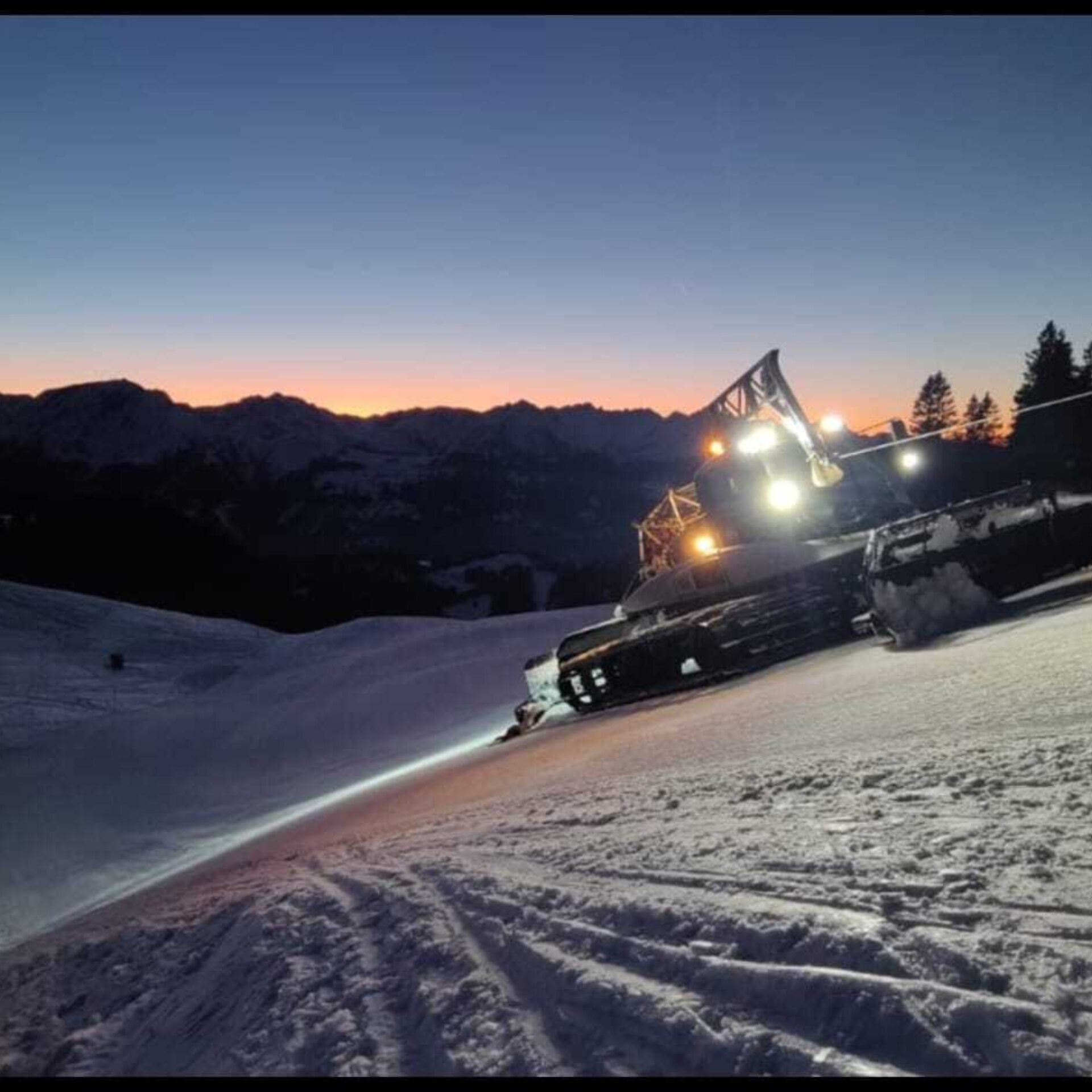 Pistenfahrzeug nach Sonnenuntergang in der Nacht