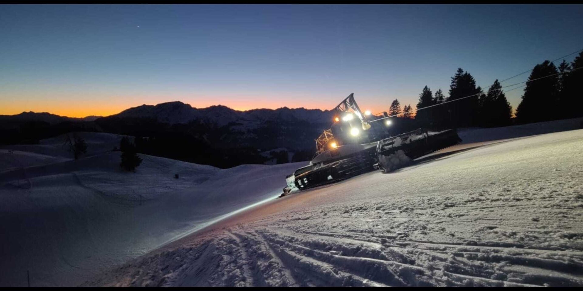 Pistenfahrzeug nach Sonnenuntergang in der Nacht