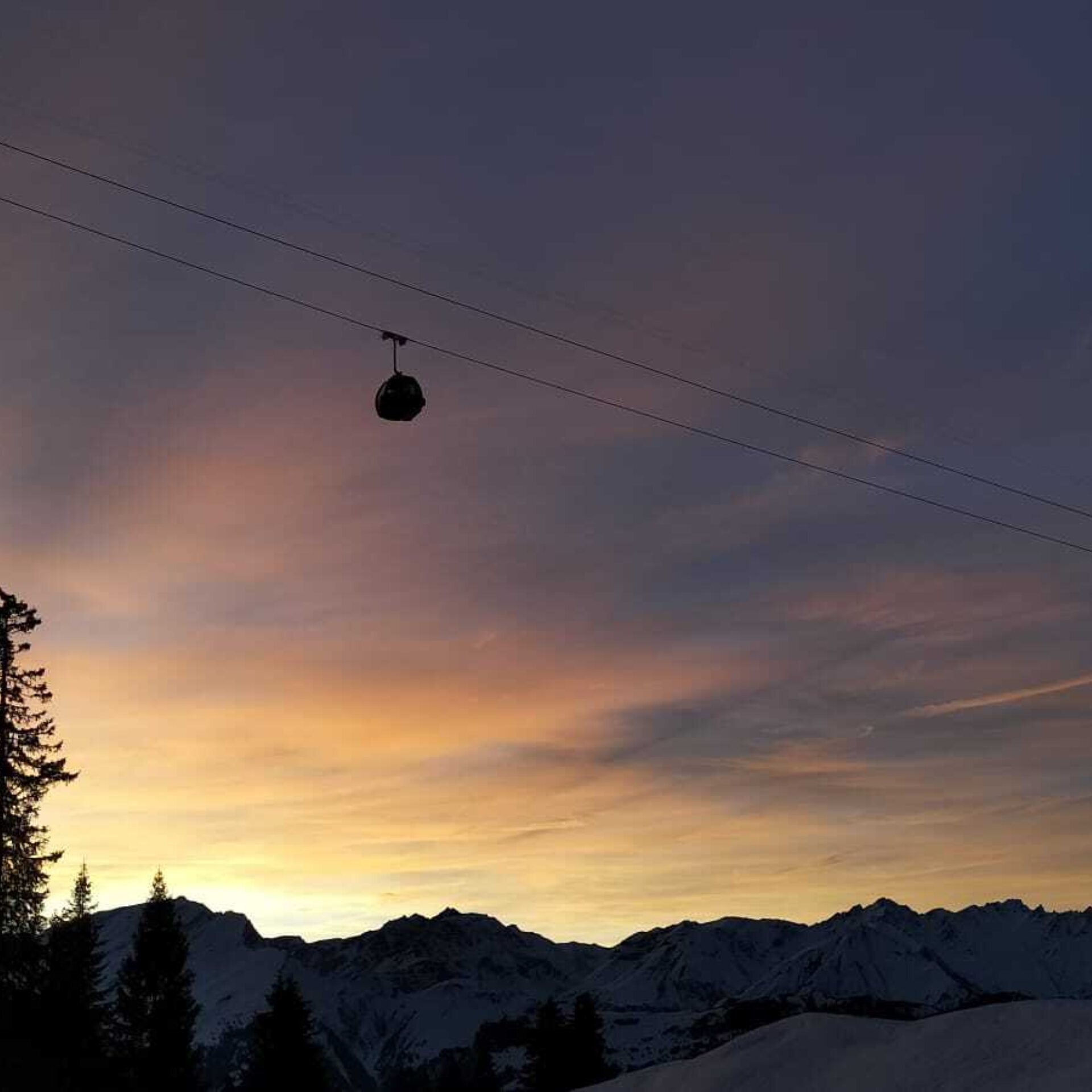 Zwei Gondelbahnen hoch vor dem farbigen Himmel