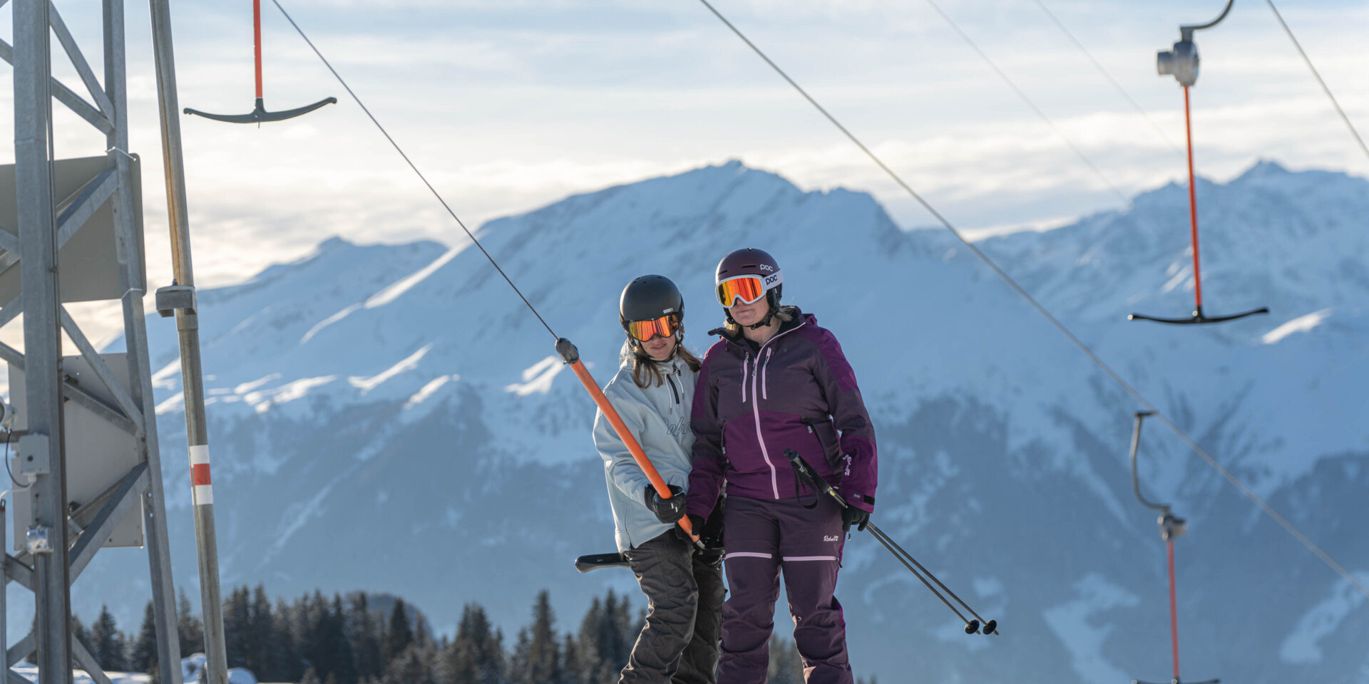 Eine Skifahrerin und eine Snowboarderin auf dem Buegellift