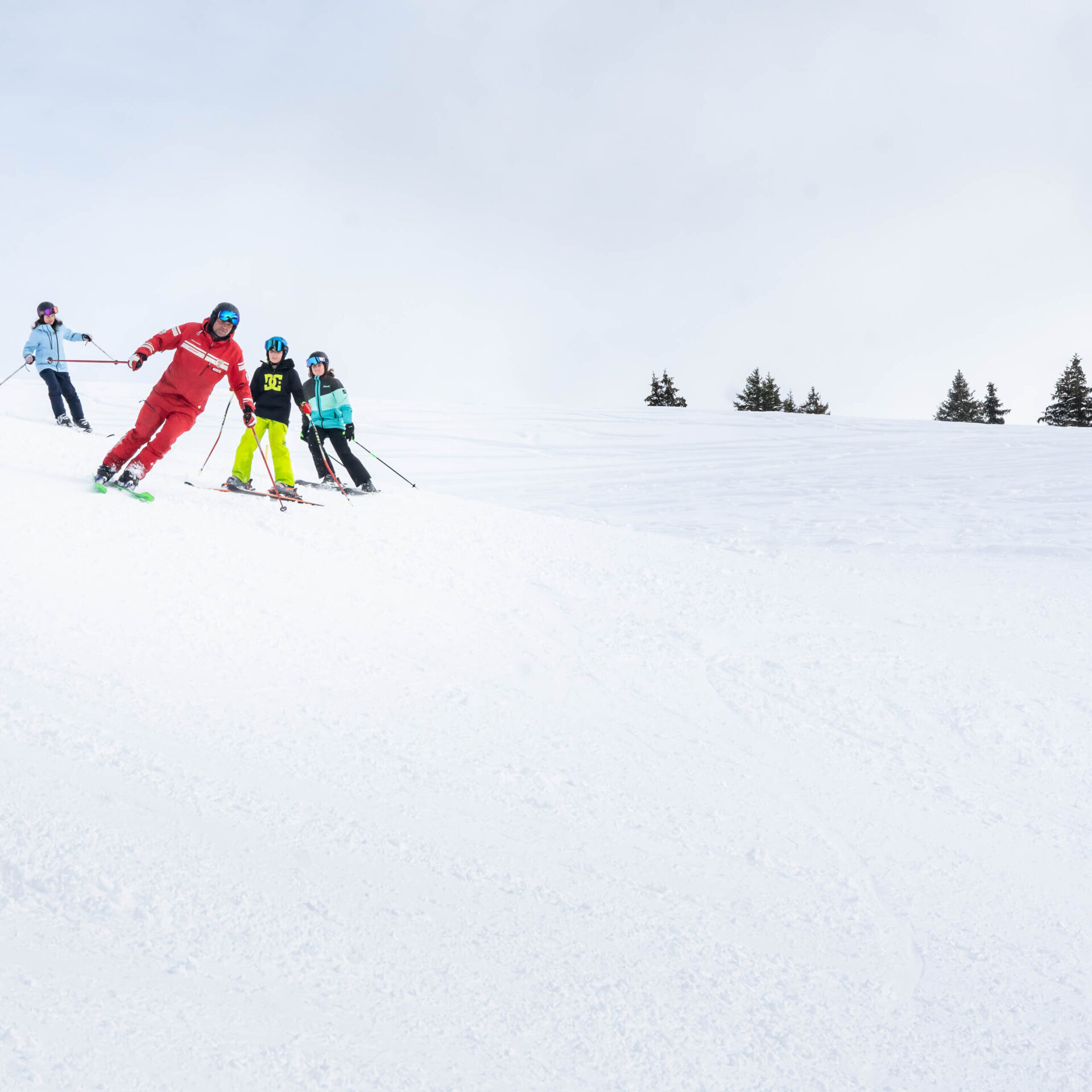 Skilehrer faehrt drei Kindern vor