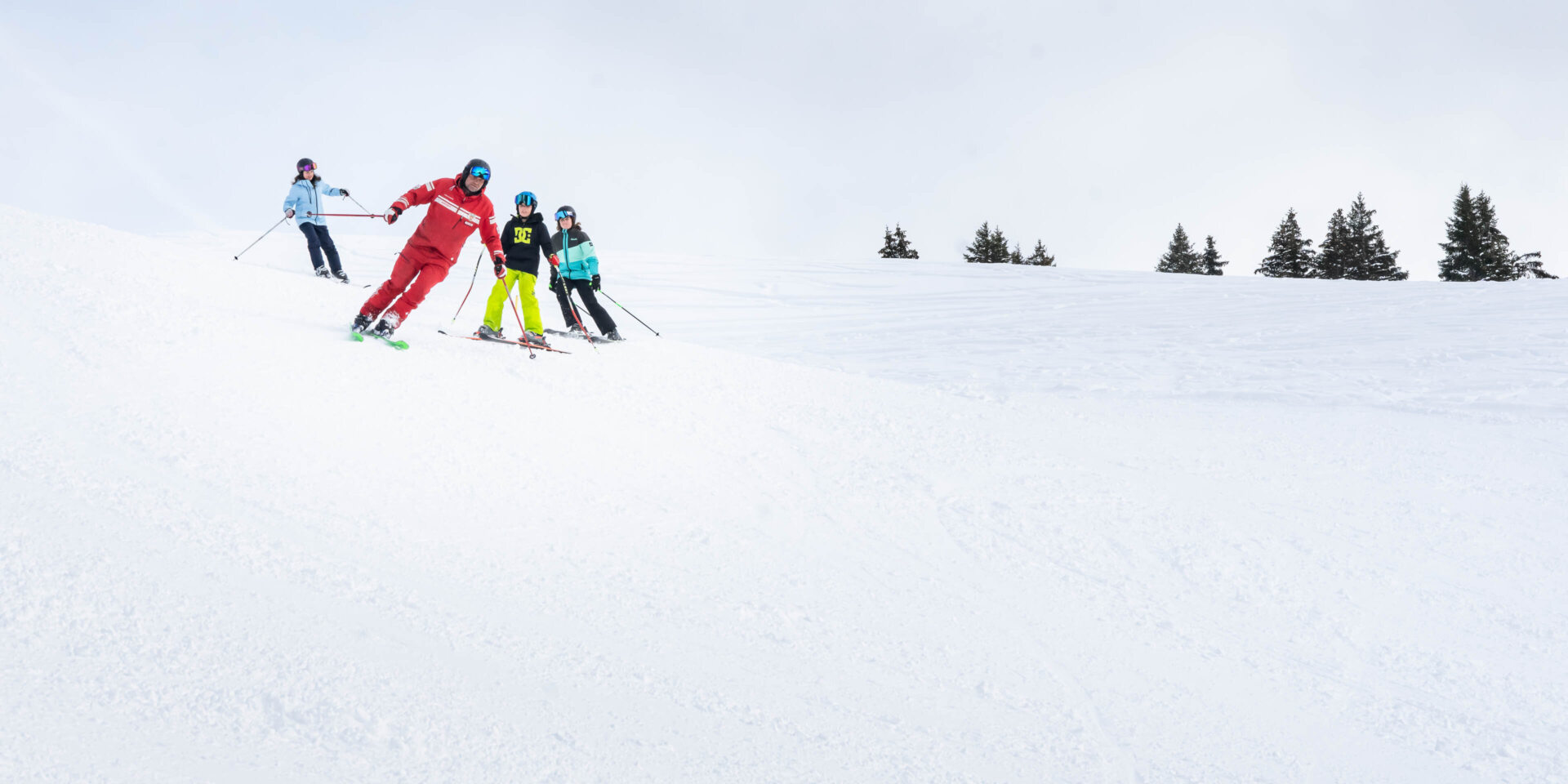 Skilehrer faehrt drei Kindern vor