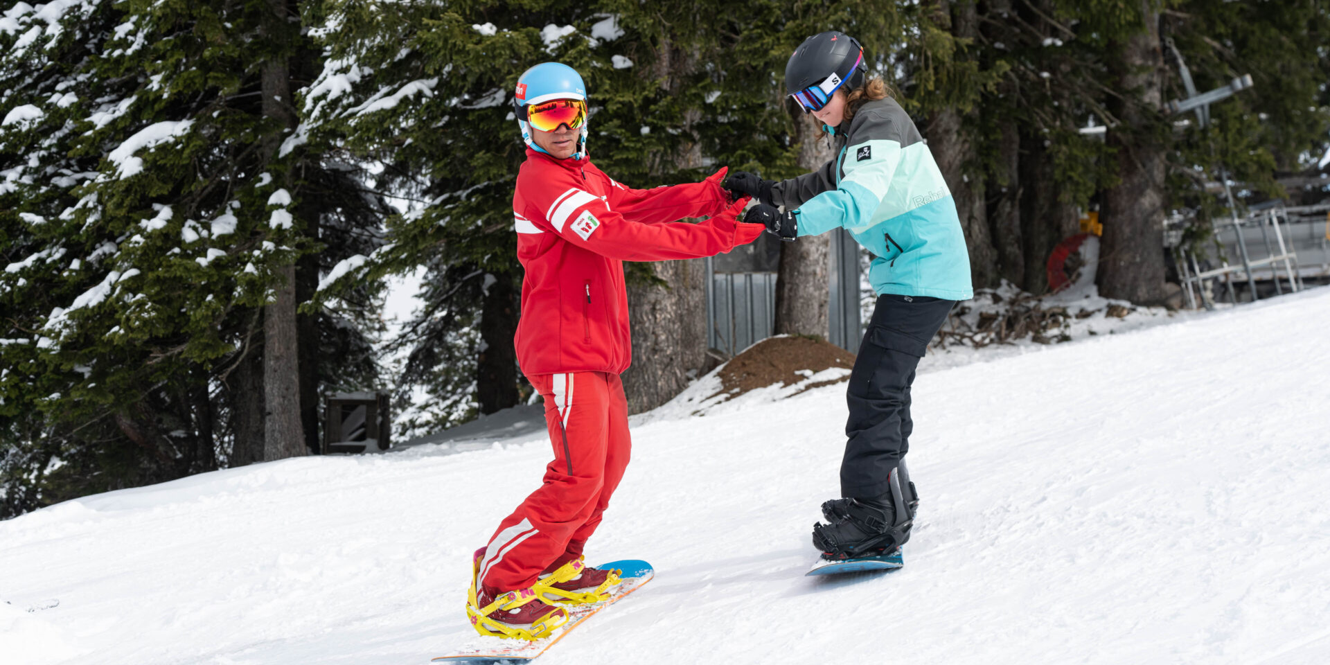 Snowboardlehrer faehrt mit seiner Schuelerin an den Haenden