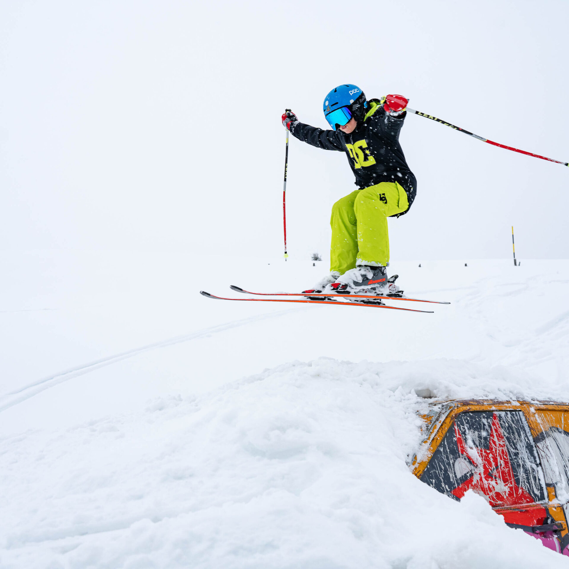 Junger Skifahrer springt ueber das Auto im Fun Park