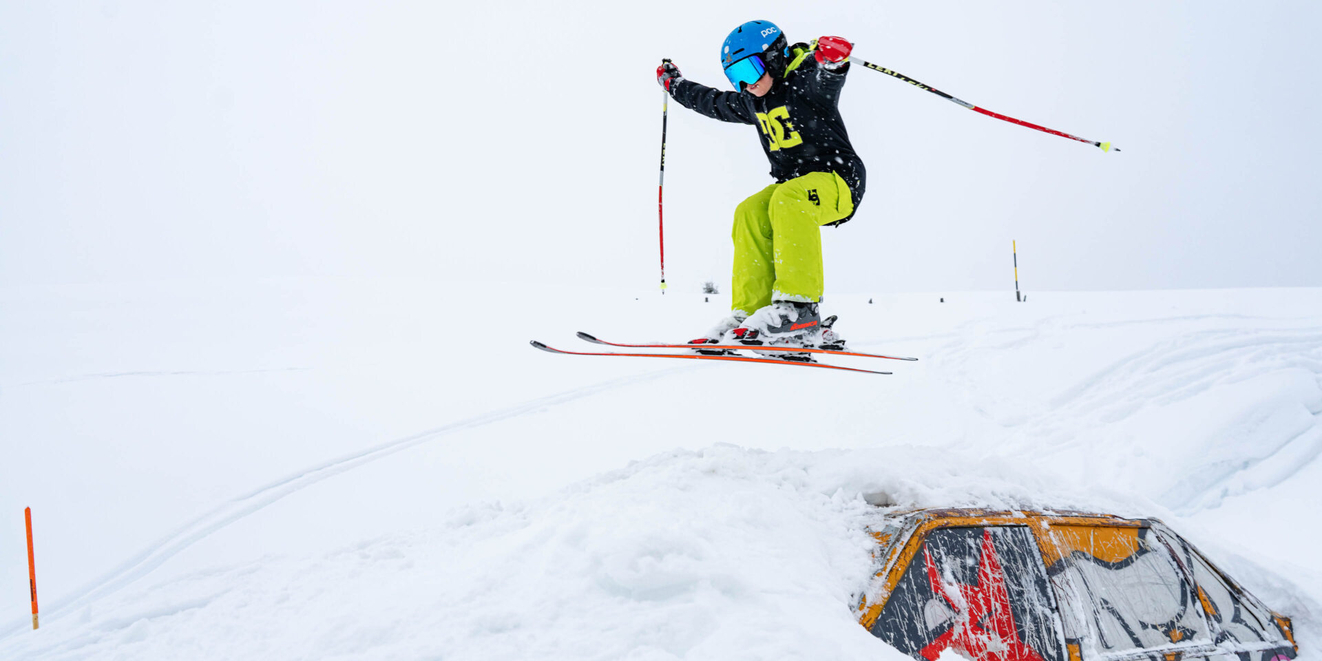 Junger Skifahrer springt ueber das Auto im Fun Park