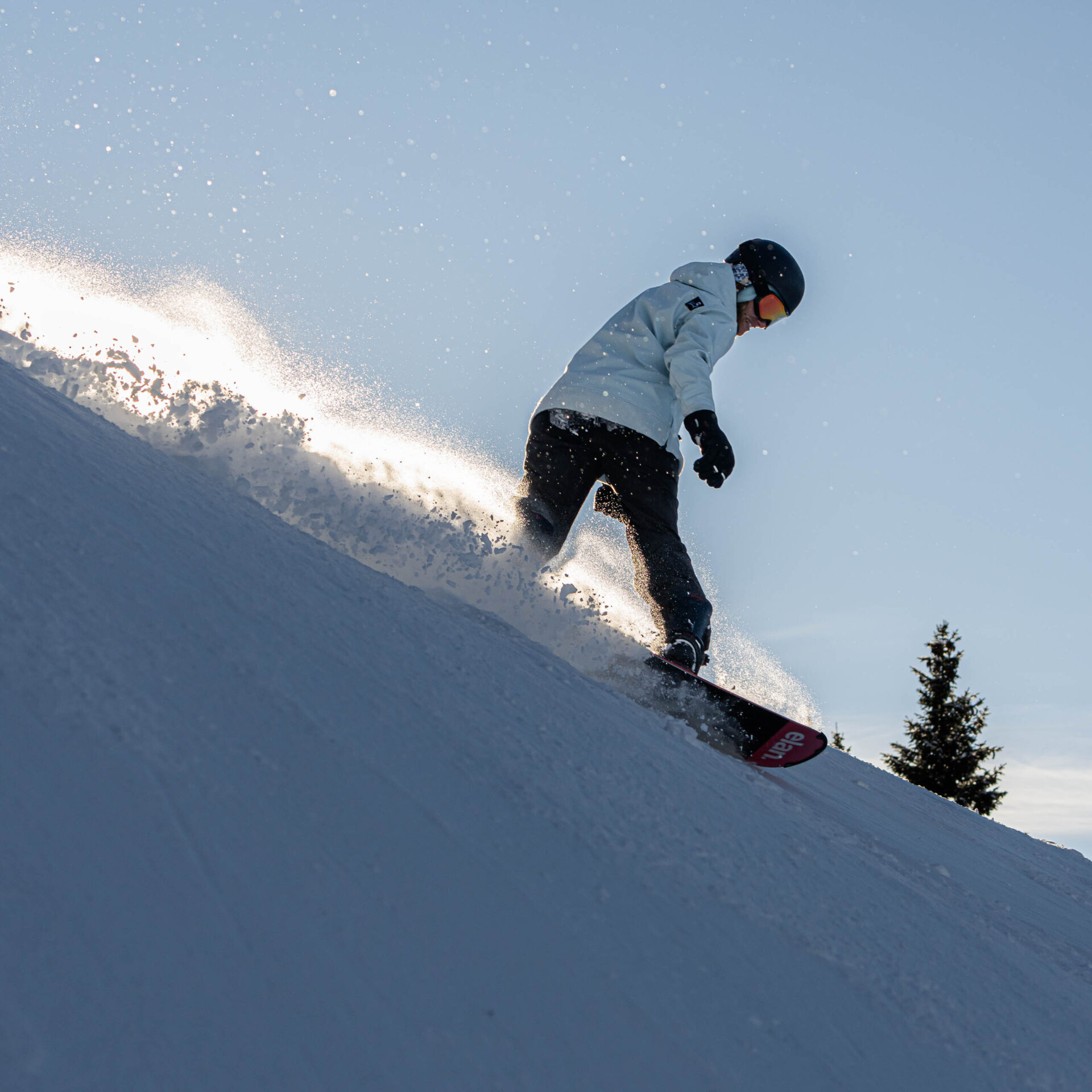 Snowboarderin mit aufgewirbeltem Schnee