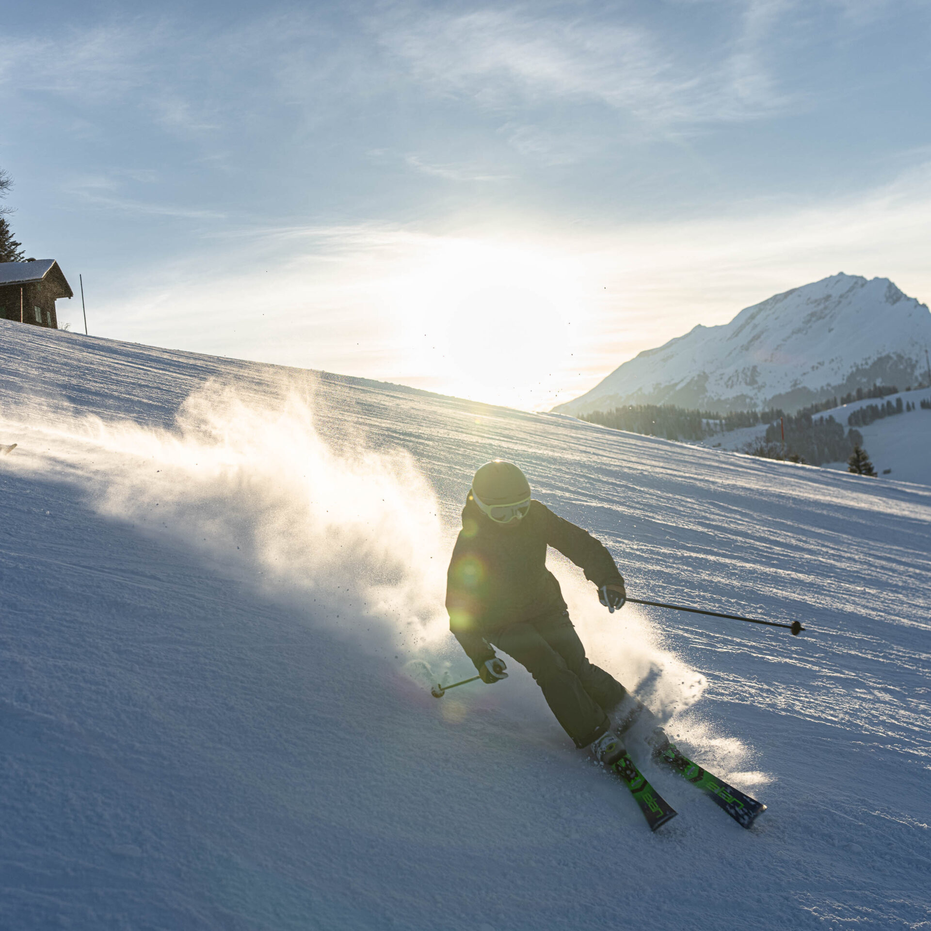 Zwei Skifahrerinnen in der Sonne mit aufgewirbeltem Schnee