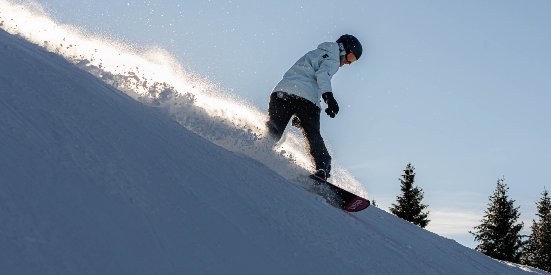 Snowboarderin mit aufgewirbeltem Schnee